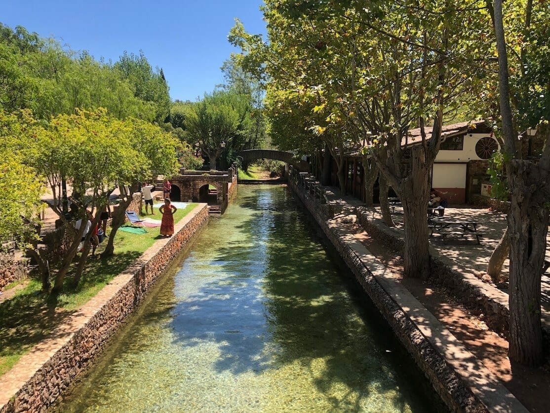 A natural pool in Alte, Algarve, that has translucid water and is surrounded by trees 