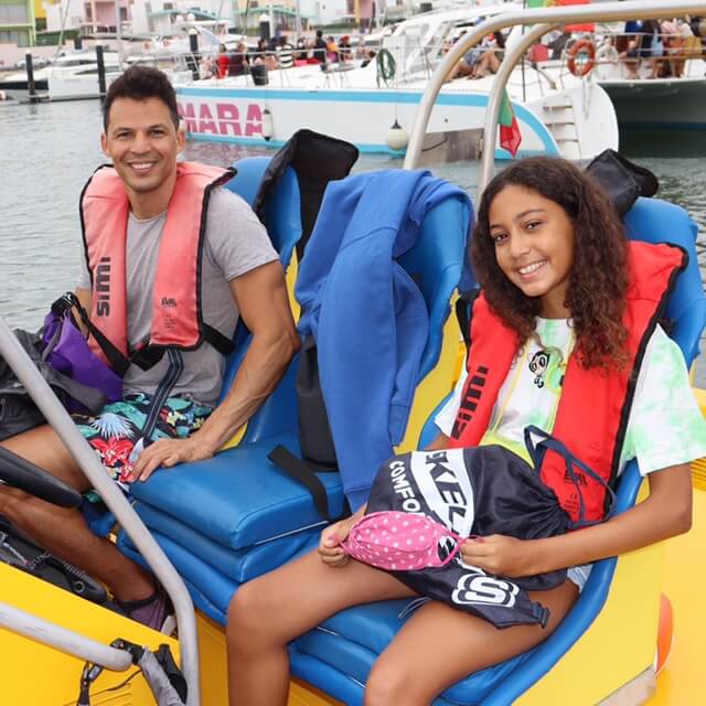 um homem e uma adolescente sentados em um barco na marina de Albufeira para fazer um passeio de observação de golfinhos