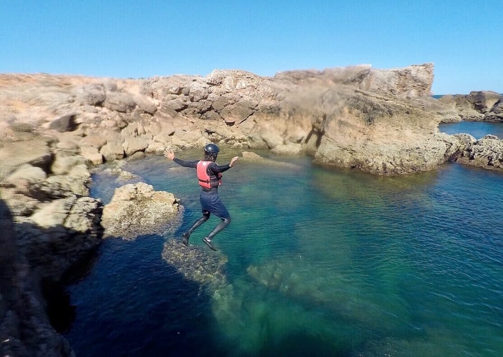 A man jumping int he water from a sea-cliff in Sagres, Algarve, Portugal