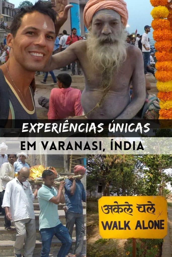 um sadhu com o corpo pintado com cinzas usando um turbante rosa-alaranjado colocando a mão na cabeça de outro homem usando uma camiseta cinza e um colar de prata, seis homens carregando um cadáver envolto em panos dourados brilhantes em uma maca de bambu e uma placa amarela escrita ande sozinho e algumas árvores atrás dela