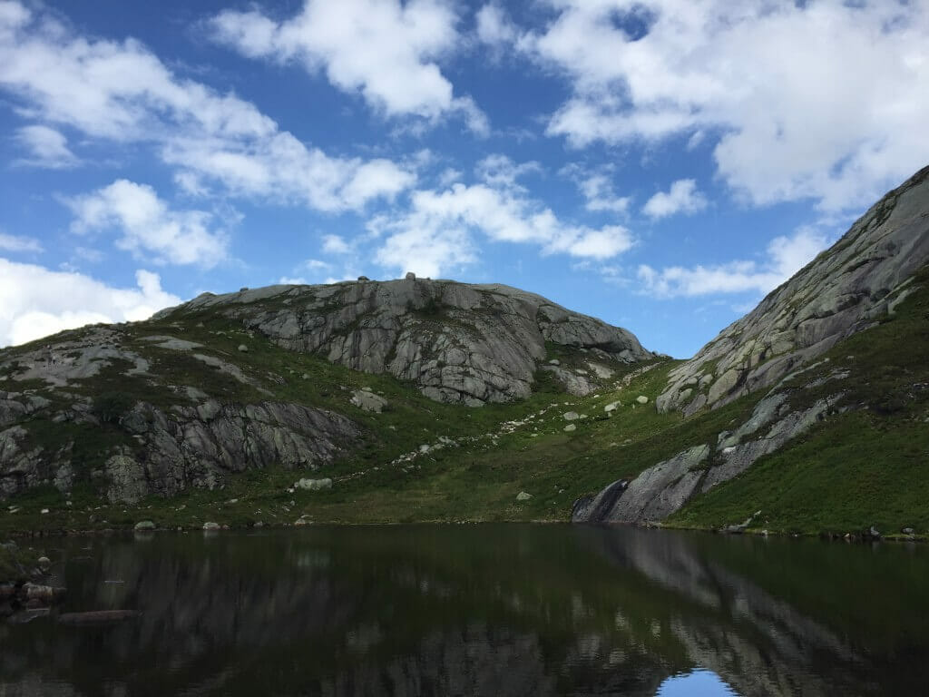 A lake surrounded by rocky mountains partially covered with grass on Kjerag Mountain, Norway