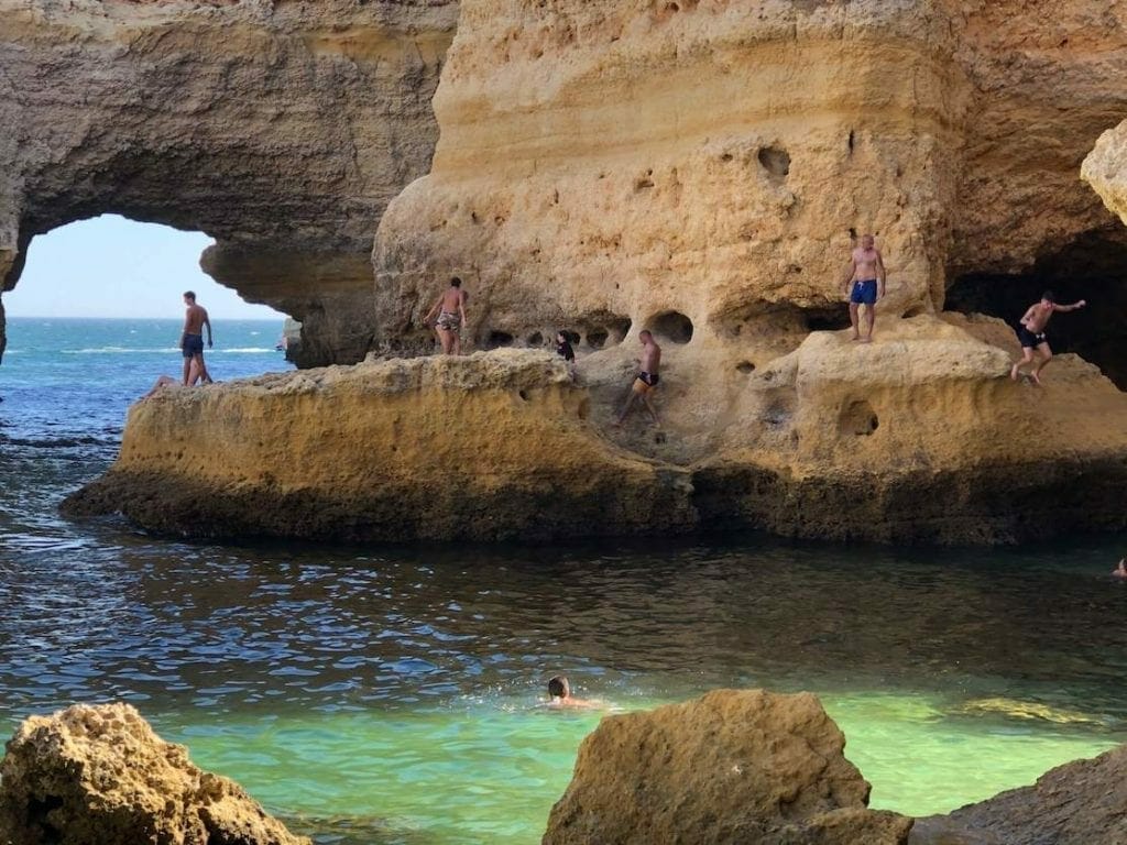 Some people walking and jumping from the cliffs in the water on Praia da Marinha