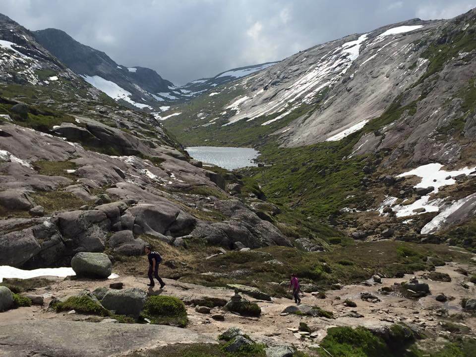 Two people walking on the gravel path of a valley during the Kjerag hike