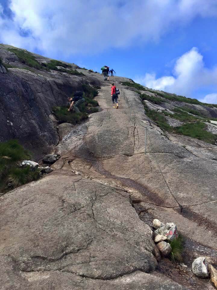 Three people climbing up Kjerag Mountain in Norway