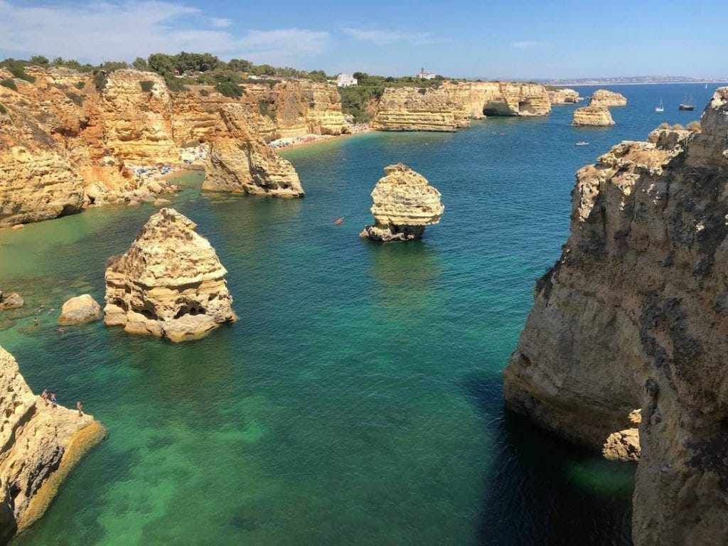 Praia da Marinha, Lagoa, is bordered by massive orange-yellowish limestone cliffs has crystal-clear green water and some tall cliffs emerging from the water