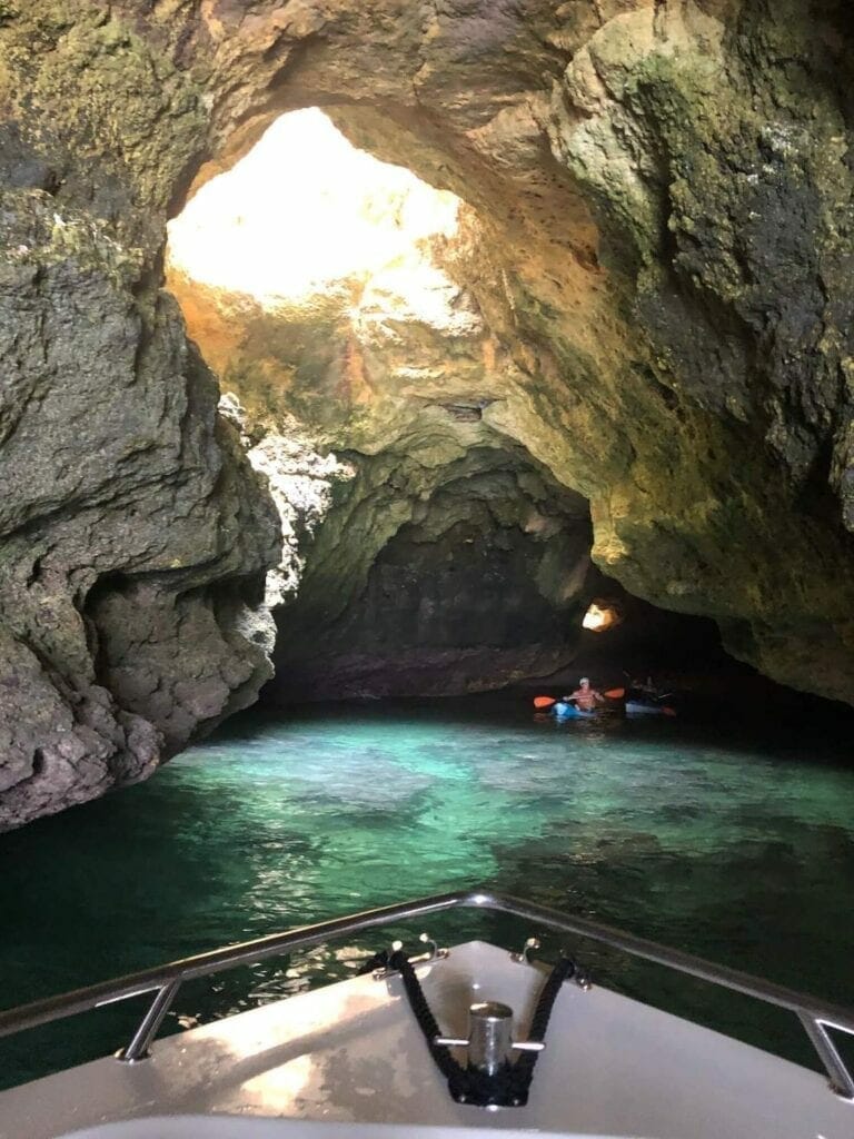 a boat and a man on kayak inside a sea cave in the Algarve, Portugal
