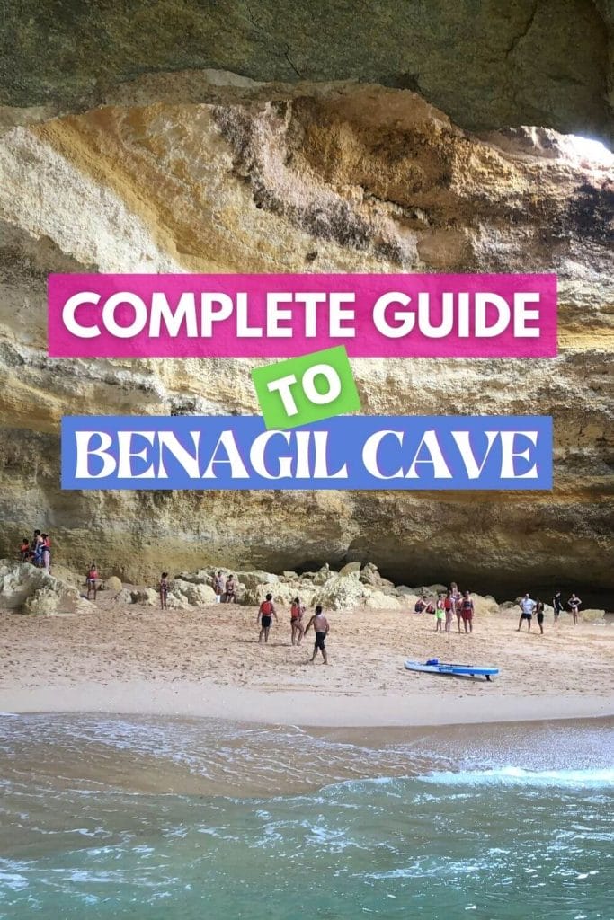 A paddleboard and some people walking inside Benagil Cave, Portugal, with its yellowish walls and round hole in the ceiling