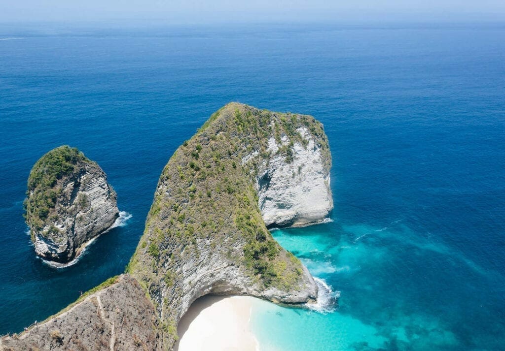 Praia Kelingking, na Ilha de Nusa Penida, e suas falésias cobertas por vegetação e água azul-turquesa cristalina