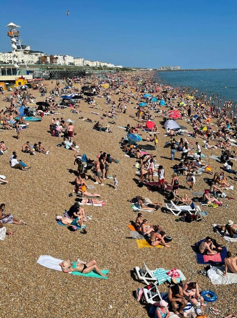 People sunbathing on the pebbles of Brighton Beach, England, UK