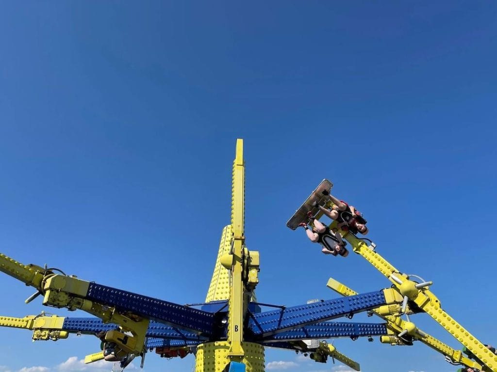 Two people seating upside down riding an Air Race on a waterfront theme park at Brighton Palace Pier, Brighton, England