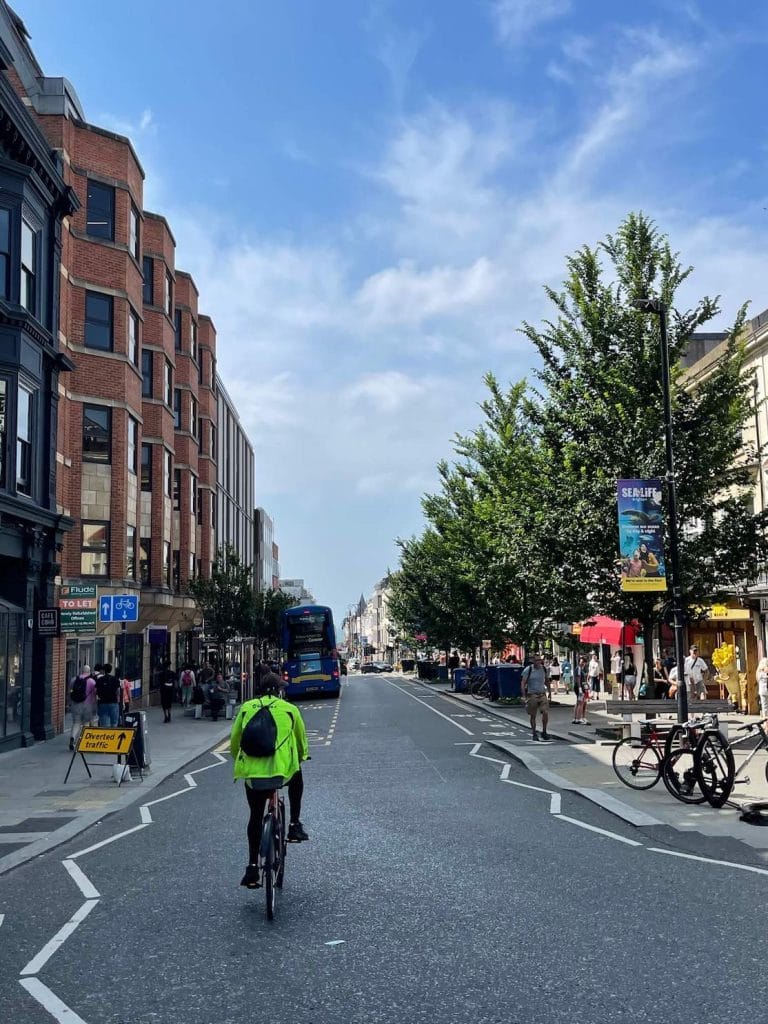 Um homem usando uma jaqueta verde pedalando em Queens Road, Brighton