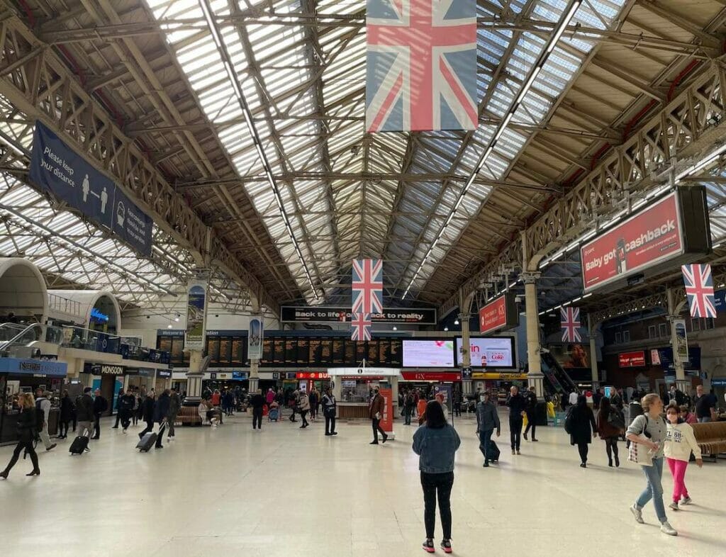 People walking at London Victoria and some England's flags hanging on the ceiling