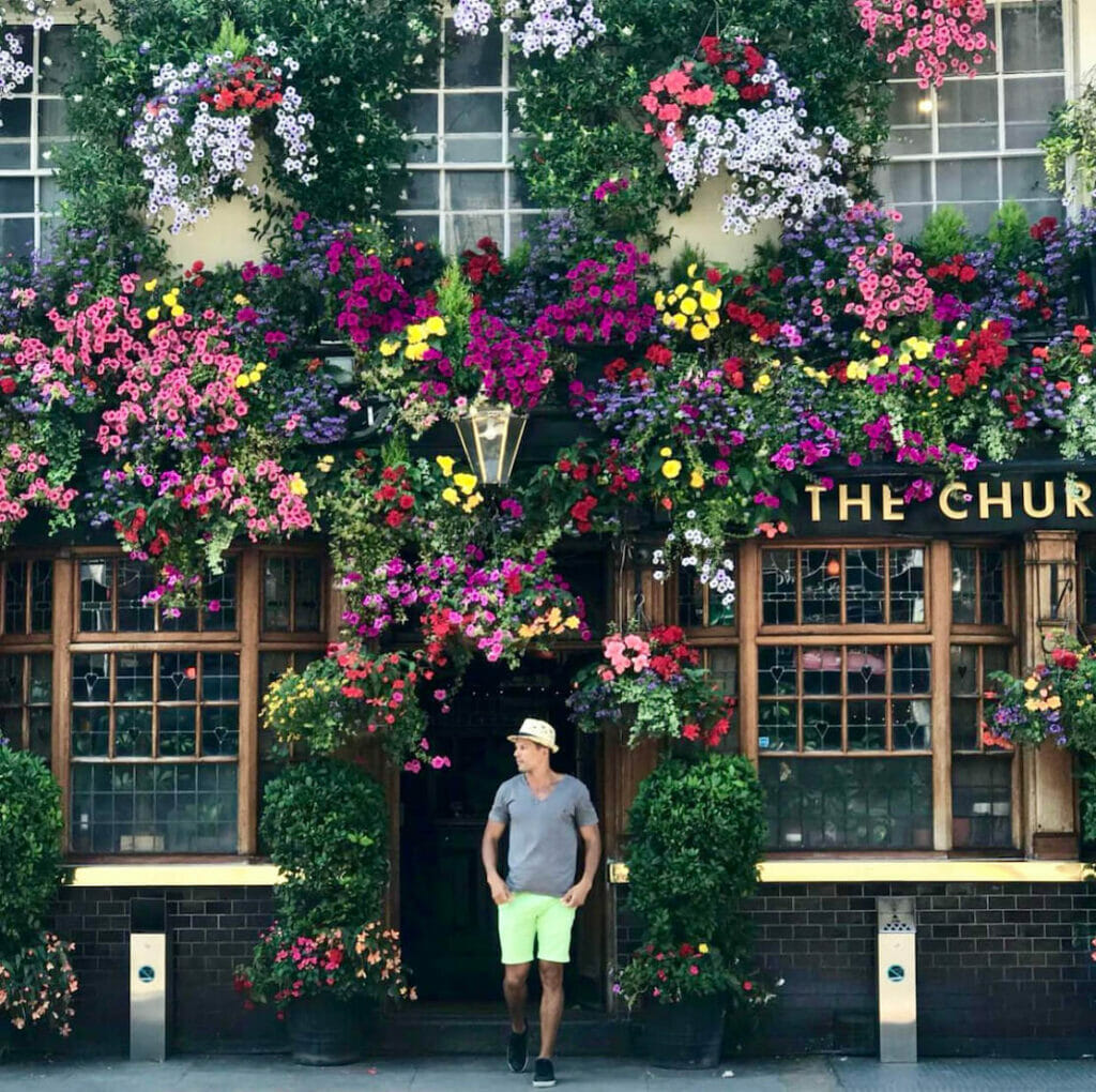 A man poses at The Churchill Arms Pub & Restaurant, a famous place to take pictures in London