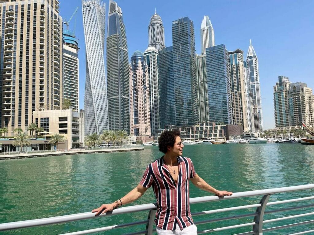 Pericles Rosa posando para una foto en Dubai Marina Walk con unos enormes rascacielos como telón de fondo