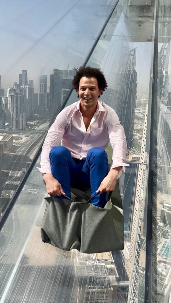 A man sliding on a glass slide at Sky Views, Dubai