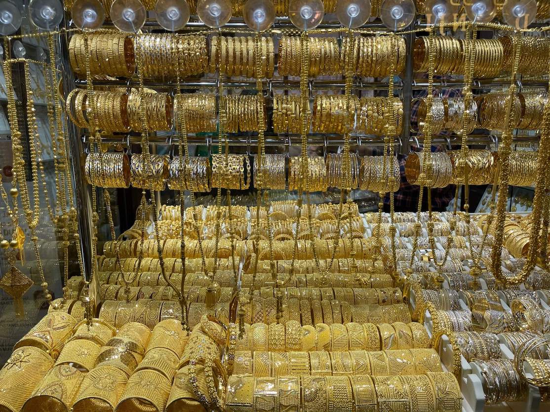 Golden bracelets and necklaces displayed in a window of a store at the Gold Souk, Dubai