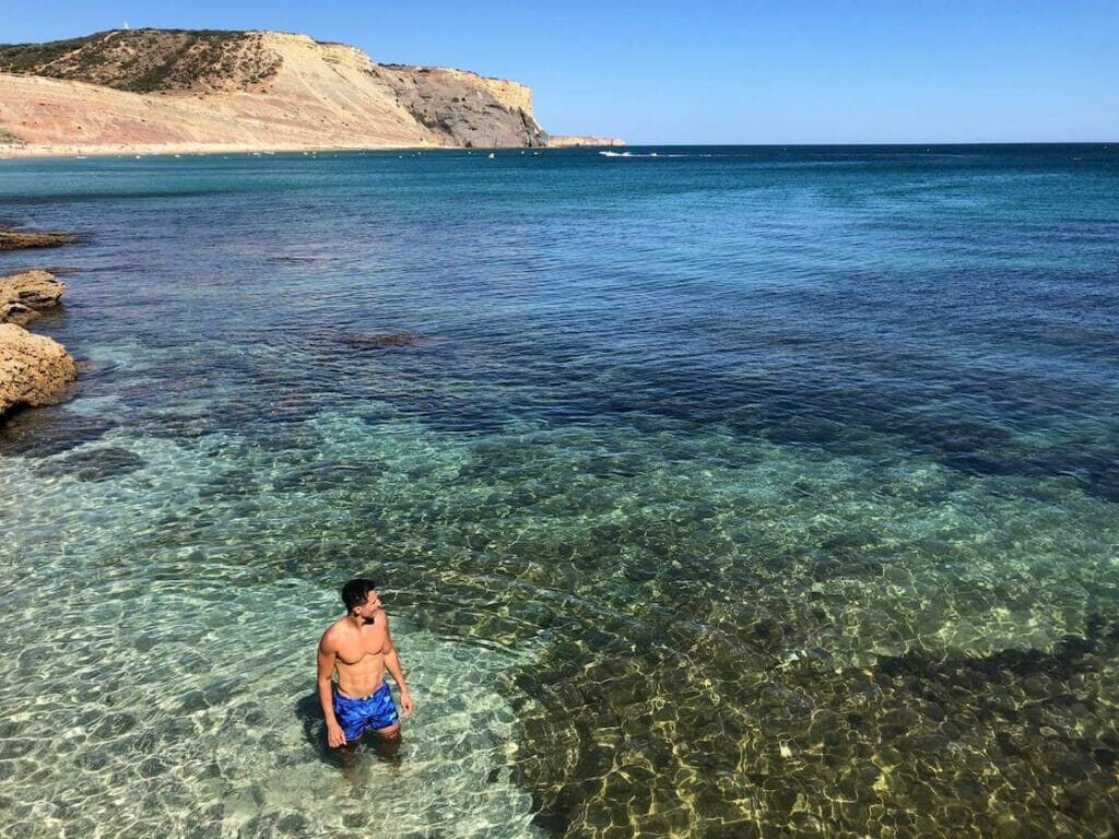 Pericles Rosa wearing blue shorts in the crystalline waters of Praia da Luz, Lagos, Portugal