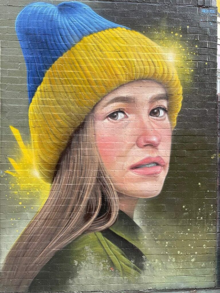 Um mural de grafite com uma foto super realista de uma mulher usando um gorro com as cores da Ucrânia pintado por Woskerski, em Redchurch Street, Londres