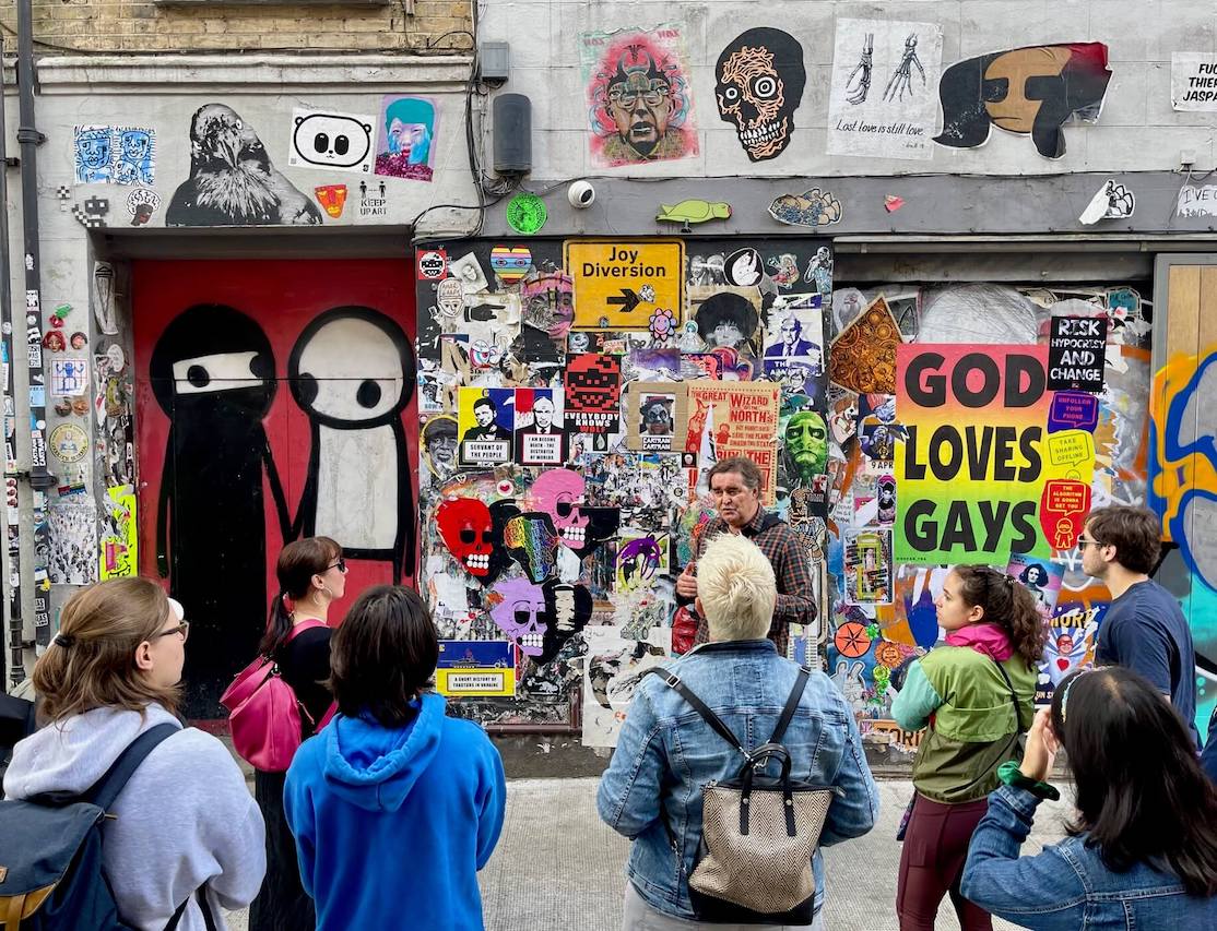 Algumas pessoas com um guia turístico observando as obras de arte exibidas em Princelet St, Londres
