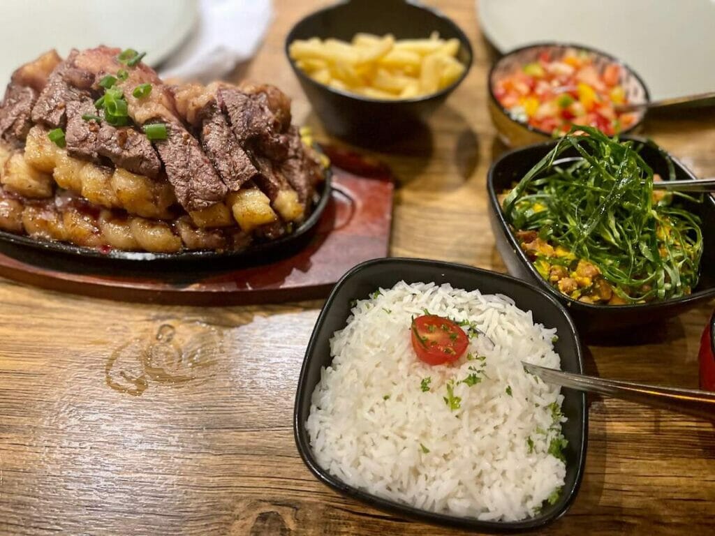 A succulent picanha (rump steak) with rice, beans, fries and salad served at Frigideira Restaurant, London