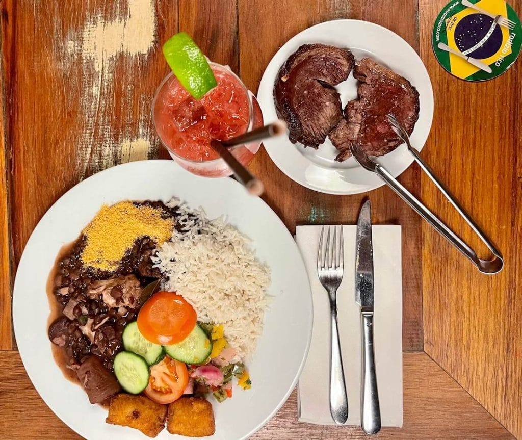 Um prato com comida brasileira e um copo de caipirinha de morango servido no Rodizio Rico, O2 Peninsula, Londres