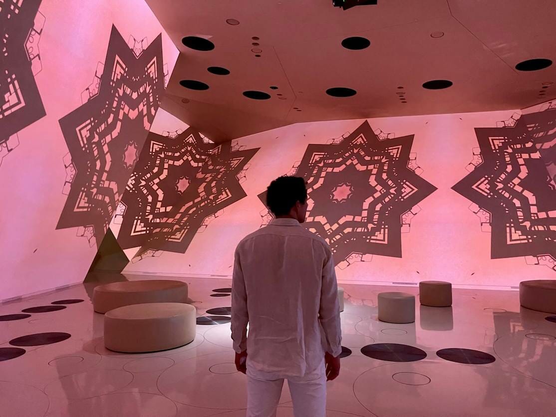Um homem assistindo um filme sendo projetado no Museu Nacional do Catar, Doha