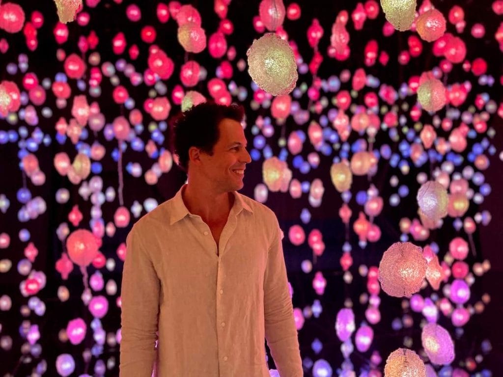 Pericles Rosa rodeado de coloridos cristales colgantes durante la Exposición Pipilotti Rist en el Museo Nacional de Qatar, Doha