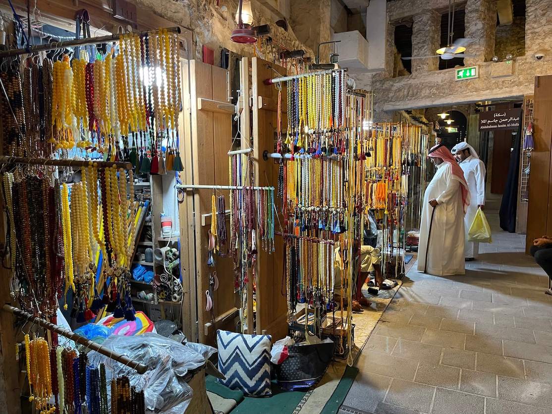 Dois homens usando trajes tradicionais fazendo compras em Souq Waqif, Doha, Catar