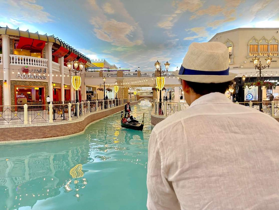 Um homem observando algumas pessoas fazendo um passeio de gôndola no Villagio Mall, Doha, Catar