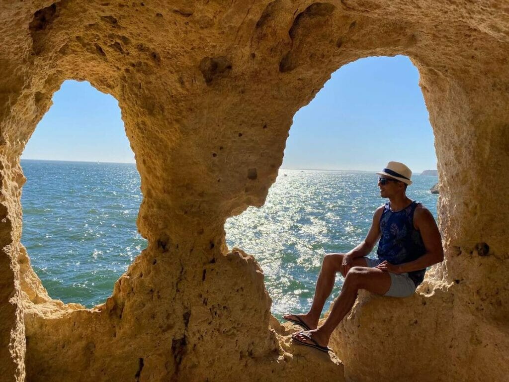 Um homem dentro de A Boneca, uma gruta com dois arcos erodidos que proporcionam excelentes vistas sobre o mar, em Algar Seco, Carvoeiro, Portugal