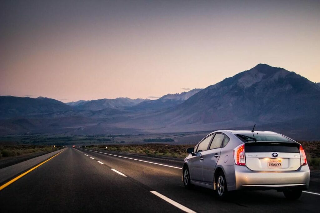 A Toyota Prius on a road with mountains as a backdrop