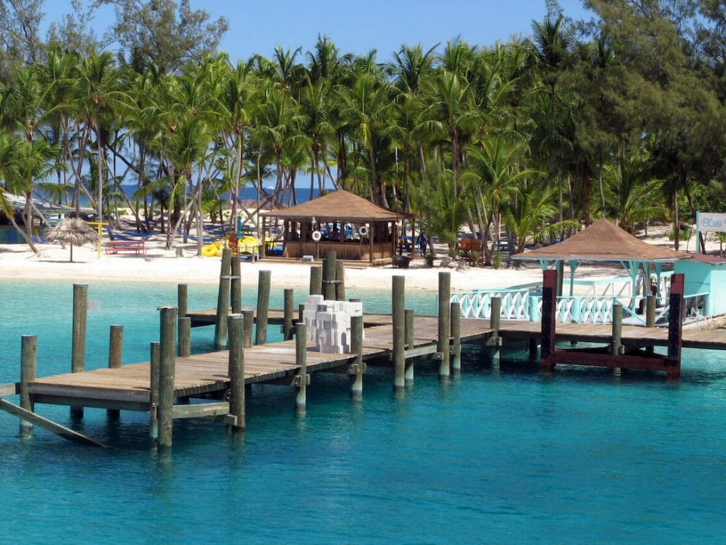 A small dock extends off a beach on Blue Lagoon Island in the Bahamas. The turquoise water of the Caribbean is warm and inviting to the thousands of tourists who flock to the Bahamas every year. The island is home to beautiful and relaxing beaches, water sports, and other activities.