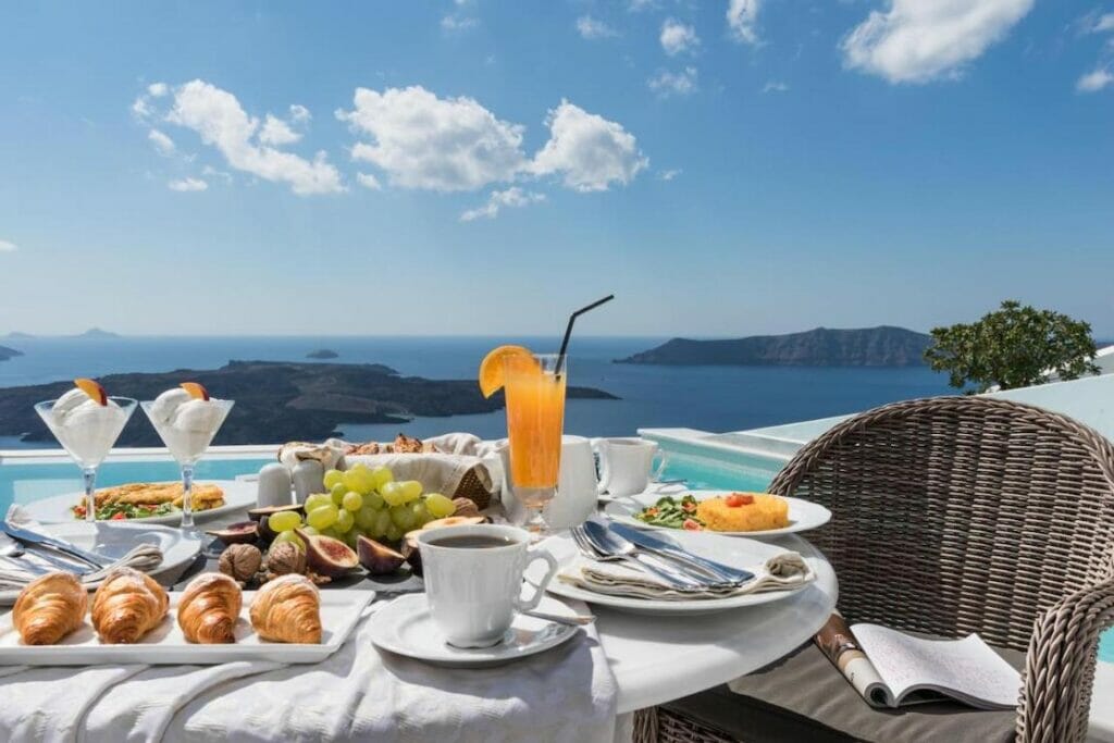 Desayuno servido junto a la piscina con la caldera y el mar Egeo de fondo en Anteliz Suites, Fira, Santorini