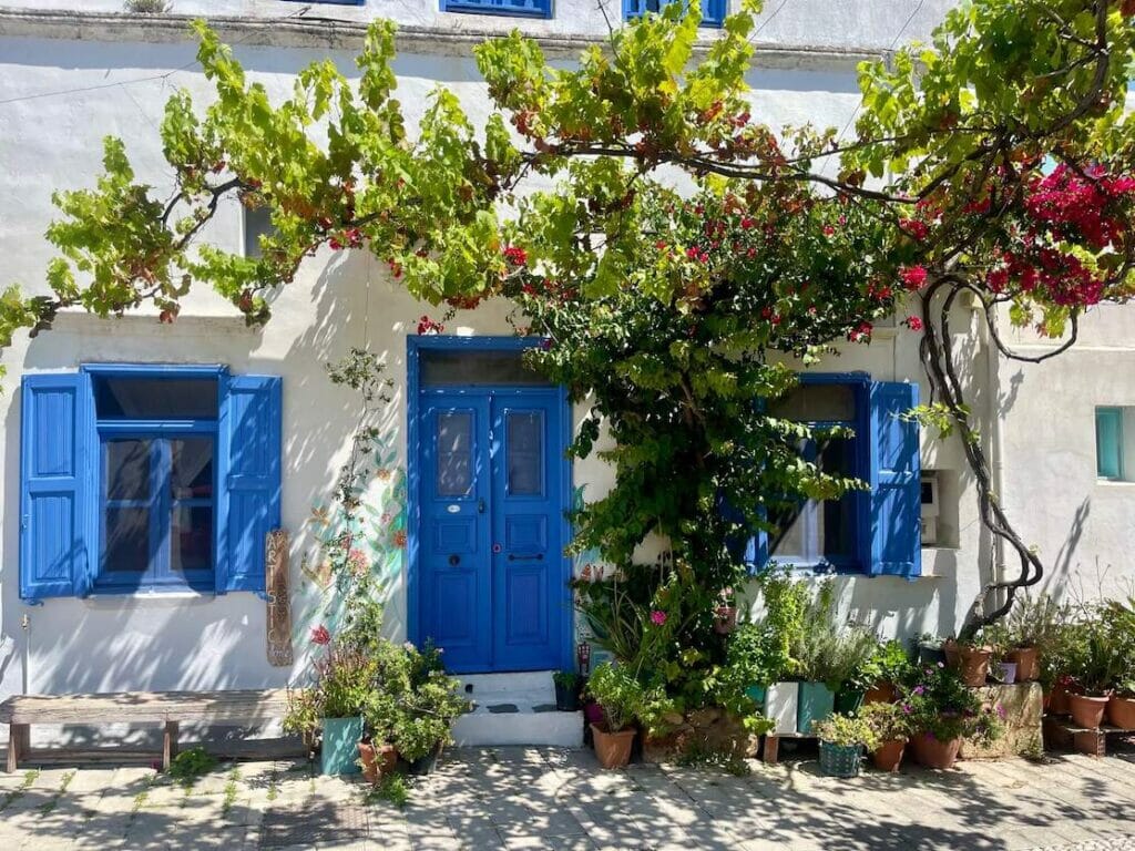 Uma casa caiada de branco com portas e janelas azuis na aldeia de Koskinou, Rodes, Grécia