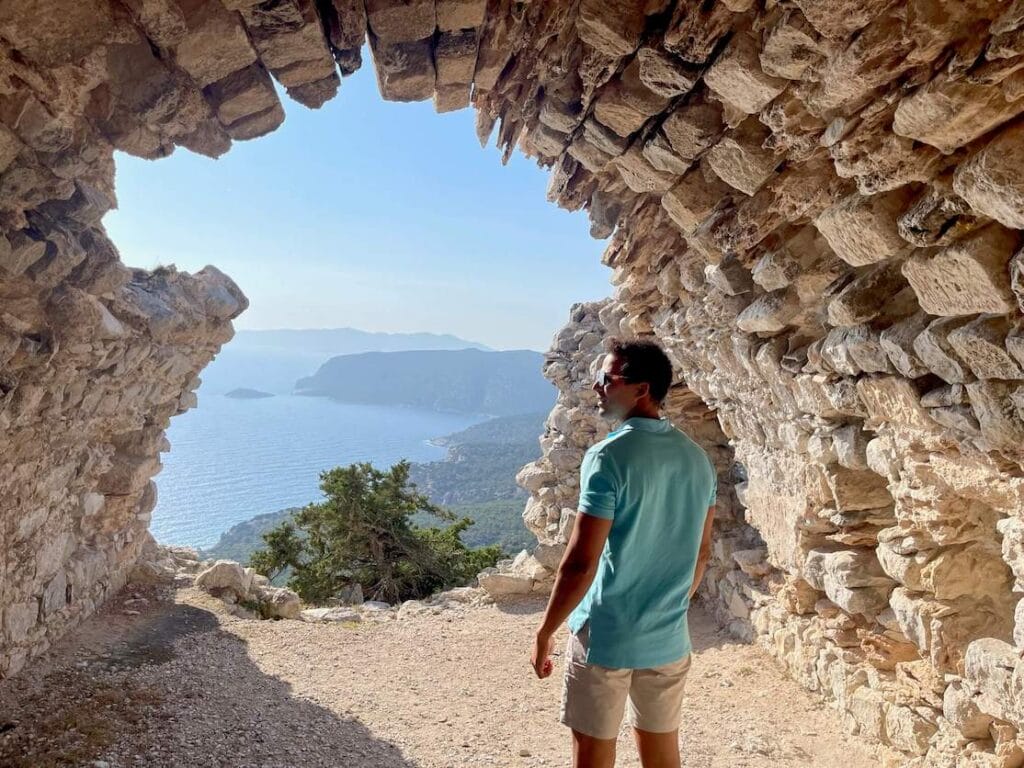 Pericles Rosa, vestido con un polo azul y pantalones cortos beige, en las ruinas de Monolithos,
Castillo, Rodas, Grecia