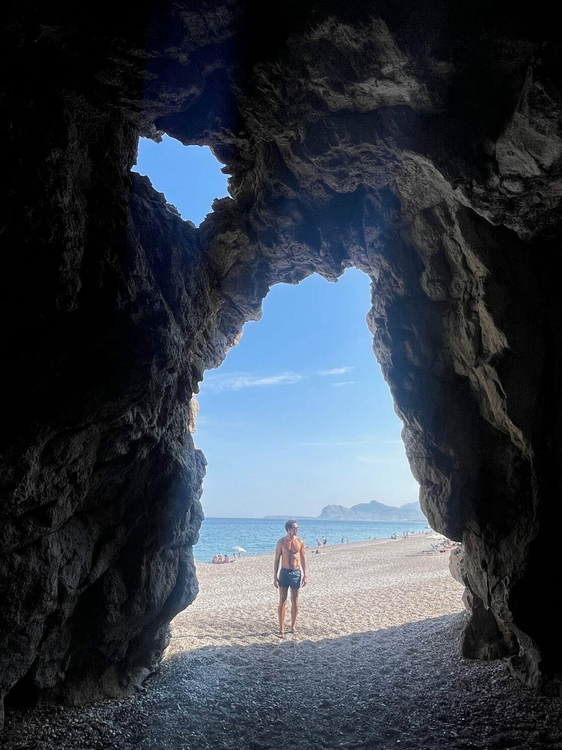 A man posing for a picture at Traganou Beach cave, Rhodes, Greece