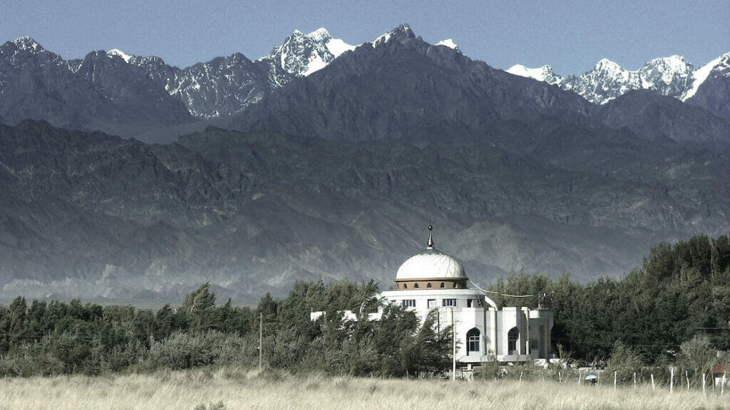a mosque surrounded by snow-peaked mountains in Xinjiang, China
