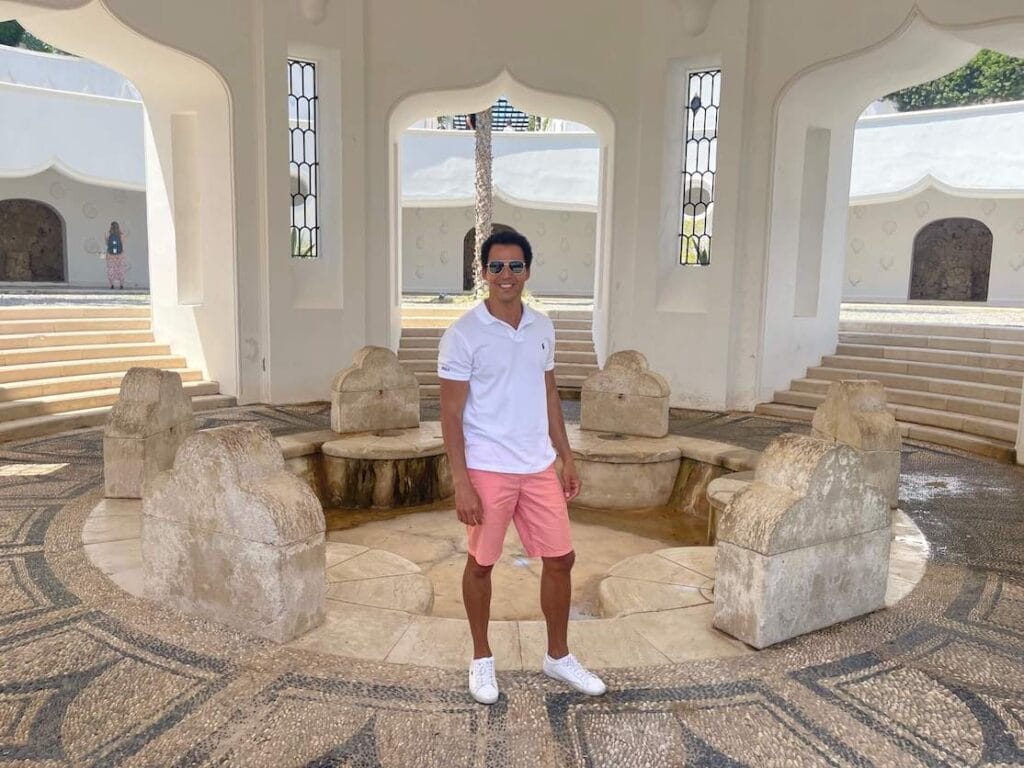 Pericles rosa usando óculos escuros, polo branco, shorts salmão e tênis branco em Kalithea Springs, Rhodes, Grécia