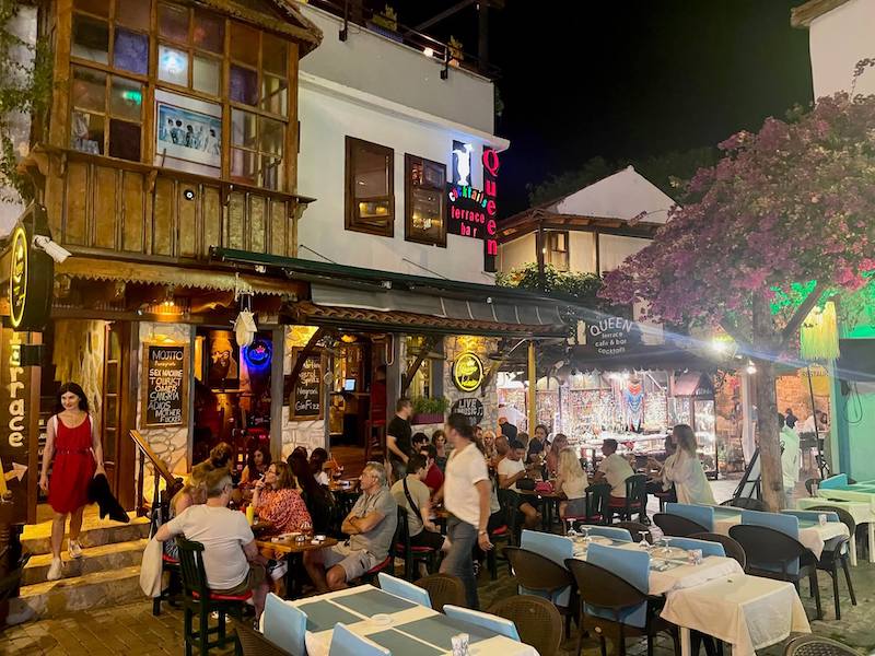 People sitting on outside tables in a square in front of Queen Bar, Kas, Turkey