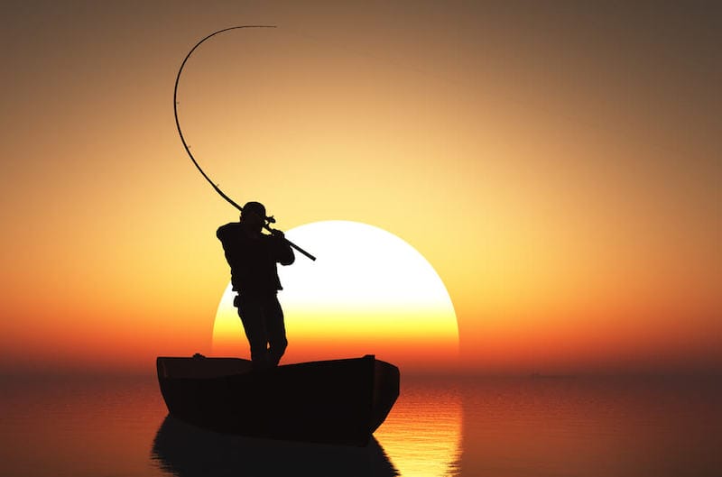 Fisherman silhouette on a boat at sunset