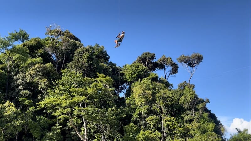 A man zip lining over Ribeira Beach, Itacare, Bahia, Brazil