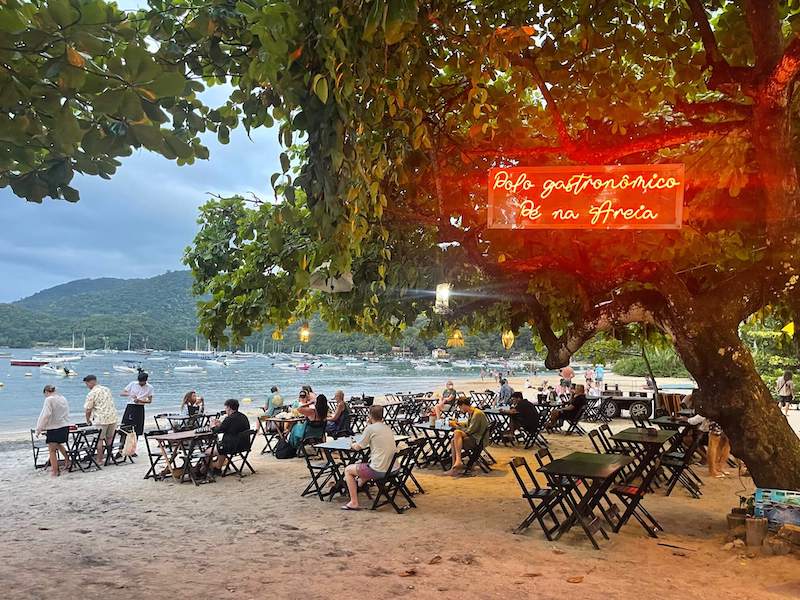 Mesas y sillas bajo un árbol en el pueblo de Abraao, Ilha Grande, Río de Janeiro, Brasil