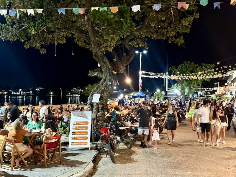 Outdoor waterfront dining at night with crowds, street food stalls, and festive lights in Barreirinhas, Maranhao, Brazil