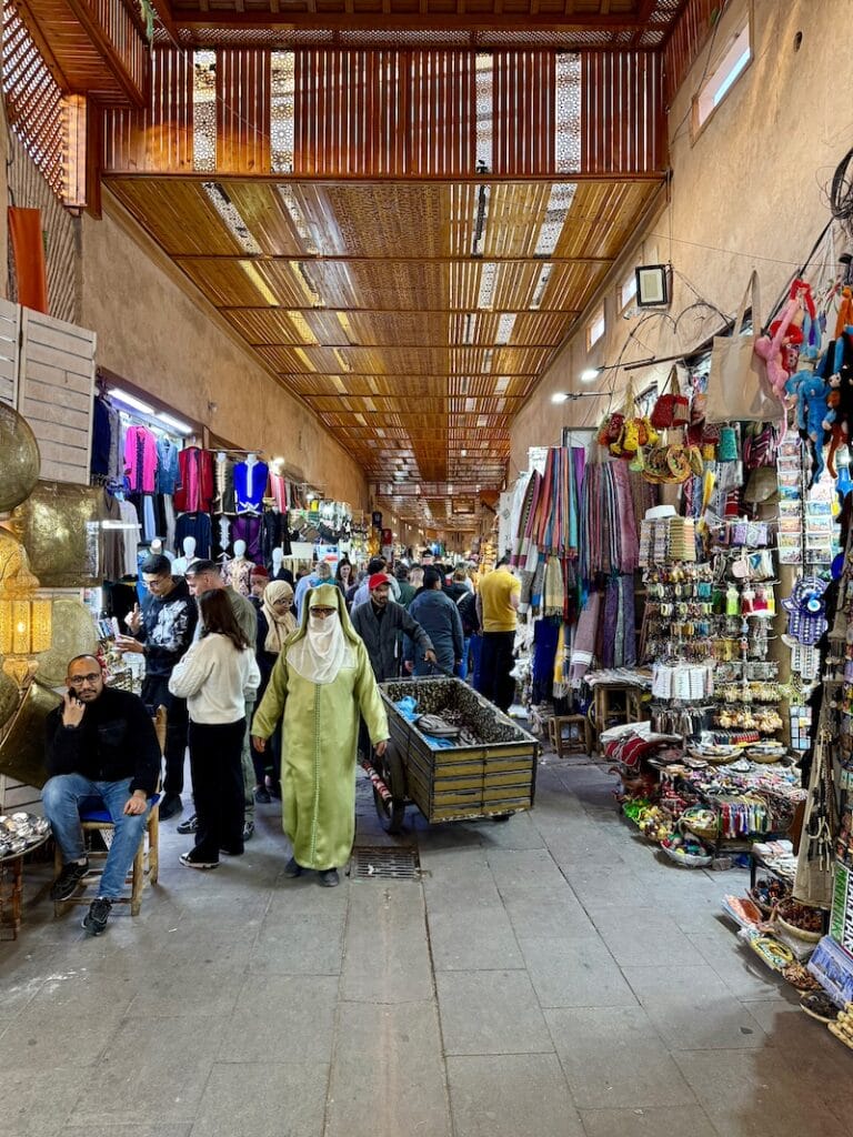 People walking on a narrow street in Marrakech's souks among stores and merchant products, Marrakech, Morocco